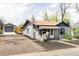 Gray bungalow with detached garage and driveway leading to backyard and quaint front porch at 4209 S Bannock St, Englewood, CO 80110