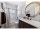 Bathroom features a vanity with stone countertop, round mirror, and bathtub-shower combo at 14953 Akron Ct, Brighton, CO 80602