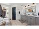 This bathroom features a double vanity with quartz countertops, stylish light fixtures, and a door to the walk-in closet at 14953 Akron Ct, Brighton, CO 80602