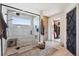 Modern bathroom features a glass-enclosed shower, neutral tile, wood cabinets, and access to the walk-in closet at 14953 Akron Ct, Brighton, CO 80602
