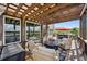 This covered deck features outdoor seating, a firepit, and views of the backyard and surrounding landscape at 14953 Akron Ct, Brighton, CO 80602