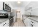 Modern kitchen boasts stainless steel appliances, white cabinetry, granite countertops, and views to the laundry room at 580 Vance St # A, Lakewood, CO 80226