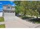 Two-story house featuring stone facade, attached garage, mature trees, and a well-maintained lawn at 4435 Andes Ct, Denver, CO 80249