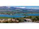 A scenic view featuring a beautiful blue lake, distant mountains, green fields, and buildings at 6110 Habitat Dr # 2, Boulder, CO 80301