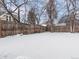 Wide view of a fenced backyard covered in snow, bordered by trees at 3398 Wadsworth Blvd, Wheat Ridge, CO 80033