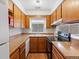 This L-shaped kitchen features wood cabinetry, dark laminate counters, and a window over the sink at 3398 Wadsworth Blvd, Wheat Ridge, CO 80033