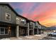 Modern condo exterior boasts stone pillars, balconies, and a sleek, dark wood facade against a vibrant sunset backdrop at 2152 Bighorn Rd # 103, Georgetown, CO 80444