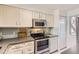 Kitchen featuring stainless steel appliances, a range, and white cabinets at 9747 W Cornell Pl, Lakewood, CO 80227