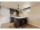 Modern kitchenette with dark cabinets, stylish backsplash, and island with seating for two at 5185 N Meade Street St, Denver, CO 80221