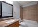 Full bathroom featuring a tub with tile surround, a decorative accent strip, and a vanity at 1365 Waxwing Ave, Brighton, CO 80601