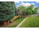 Green backyard with mature trees, a wooden fence, and a picnic table with play house at 517 Sylvestor Trl, Highlands Ranch, CO 80129