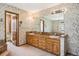 Floral wallpapered bathroom with double vanity and oak cabinets at 5106 S Kenton Way, Greenwood Village, CO 80111