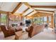 Open living room featuring exposed beams, brick fireplace, wood paneling and large windows at 5106 S Kenton Way, Greenwood Village, CO 80111