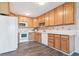 Well-lit kitchen featuring light wood cabinetry, white appliances, and a contrasting dark floor at 775 S Alton Way # 3C, Denver, CO 80247