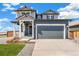 Two-story home with blue siding, a gray garage door, front porch, and professionally landscaped front yard at 2237 Garden Ave, Brighton, CO 80601