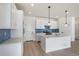 Bright kitchen with white cabinets, quartz countertops, stainless steel appliances, and island with pendant lights at 2237 Garden Ave, Brighton, CO 80601