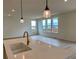 Open-concept kitchen with large island, quartz countertops, pendant lighting, and bright living area views at 2237 Garden Ave, Brighton, CO 80601