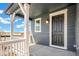 Inviting front porch with white railings, supporting columns, and a stylish black front door with a lantern at 2237 Garden Ave, Brighton, CO 80601