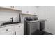 Laundry room with modern front-loading washer and dryer and a sink with white cabinets at 16135 Rock Crystal Dr, Parker, CO 80134