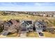 Neighborhood aerial view of single Gathering homes, green space, and city skyline in the distance at 16135 Rock Crystal Dr, Parker, CO 80134