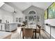 Open-concept dining area with vaulted ceilings, a modern glass table, and ample natural light from large windows at 2295 S Depew St, Denver, CO 80227