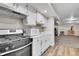 A modern kitchen boasts white cabinetry, stainless steel appliances, and wood-look floors, leading into the living area at 2295 S Depew St, Denver, CO 80227