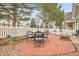 Outdoor brick patio with an umbrella-covered dining table, grill, white picket fence, and peaceful backyard at 2295 S Depew St, Denver, CO 80227