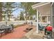 Outdoor patio featuring a brick landing, white picket fence, grill, dining table, and lounge area under mature trees at 2295 S Depew St, Denver, CO 80227