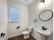 Half bathroom with sleek fixtures including a pedestal sink, modern lighting, and a stylish round mirror at 339 Rocking Chair Dr, Berthoud, CO 80513