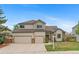 Charming two-story home with three-car garage and manicured front yard landscaping on a sunny day at 9983 Cottoncreek Dr, Highlands Ranch, CO 80130