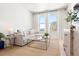 Bright living room featuring a gray sofa, glass table, light wood floors, and large windows at 2851 W 52Nd Ave # 404, Denver, CO 80221