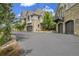 Elegant exterior view with stone accents, arched garage doors, and pristine driveway at 4158 Wild Flower Ct, Evergreen, CO 80439