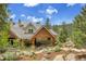 A backyard exterior elevation shows a luxury home with stone accents and covered patio seating area at 4158 Wild Flower Ct, Evergreen, CO 80439