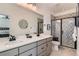 Modern bathroom featuring a double sink vanity, stylish mirrors, and a walk-in shower with decorative tile at 12301 Festival Ln, Thornton, CO 80241