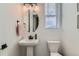 A clean powder room includes a pedestal sink, toilet, oval mirror, and natural light at 12301 Festival Ln, Thornton, CO 80241