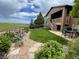 Landscaped backyard with a patio, lawn, flowerbeds, and a view of a grassy field at 15789 W 95Th Pl, Arvada, CO 80007