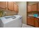 Well-lit laundry room featuring wood cabinets, tile flooring, and modern, front-load washer and dryer at 15789 W 95Th Pl, Arvada, CO 80007