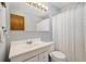 Bathroom featuring a mirror with vanity lighting, a shower with a textured curtain, and a white toilet at 1211 S Zuni St, Denver, CO 80223