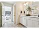 Bright bathroom featuring double sinks with white cabinets, stone floors, and a view into the bedroom at 27756 E Byers Pl, Aurora, CO 80018