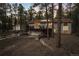 Two-story home with red roof and deck nestled among mature trees and rock landscaping features at 18045 Arrowwood Dr, Monument, CO 80132