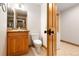 Powder room features wooden vanity with granite countertop, toilet and view of hallway at 11683 Pointe View Dr, Longmont, CO 80503