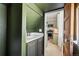 Cozy powder room featuring green walls, sleek sink, and a glimpse of the kitchen's modern appliances at 1519 E 29Th Ave, Denver, CO 80205