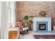 Comfortable sitting area with a brick wall fireplace, hardwood floors, and light-filled window at 1519 E 29Th Ave, Denver, CO 80205