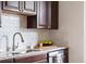 A close-up of the kitchen sink features granite countertops, dark wood cabinets and stainless steel dishwasher at 3438 N York St, Denver, CO 80205