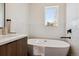 A bright bathroom featuring a soaking tub, white tile walls, and dark fixtures at 3430 W 25Th Ave, Denver, CO 80211