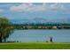 Scenic view of Sloan's Lake with a walking path and city buildings in the distance, with mountains beyond at 3430 W 25Th Ave, Denver, CO 80211