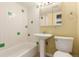 Bathroom with white and green tiled walls, a toilet, sink, mirror, and a bathtub with shower at 1450 Albion St # 204, Denver, CO 80220