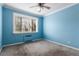 A carpeted bedroom with light blue walls, a ceiling fan, and a large window with blinds at 1450 Albion St # 204, Denver, CO 80220