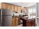 Bright kitchen with a stainless steel refrigerator, light wood cabinets, and a dark wood island at 1450 Albion St # 204, Denver, CO 80220