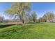 A lush community park featuring mature trees, open green spaces, and recreational facilities such as a tennis court at 4059 Nevis St, Boulder, CO 80301